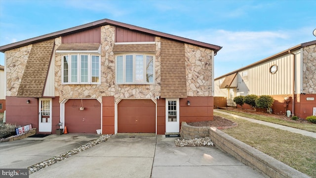 view of front of property with stone siding, driveway, and an attached garage