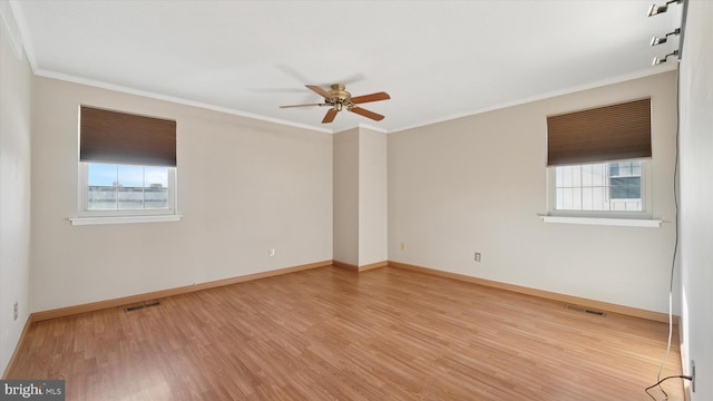 spare room featuring visible vents, plenty of natural light, crown molding, and wood finished floors