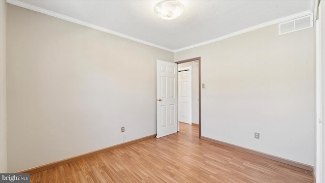 unfurnished room with crown molding, light wood-style floors, visible vents, and baseboards