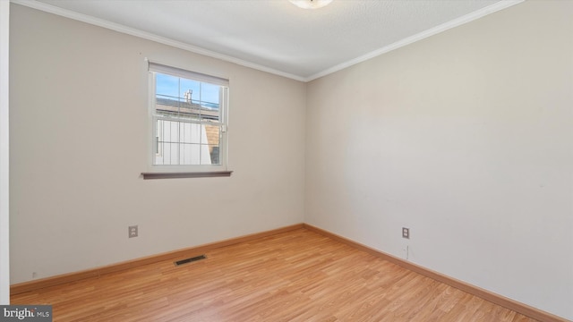 unfurnished room featuring crown molding, baseboards, visible vents, and light wood-type flooring