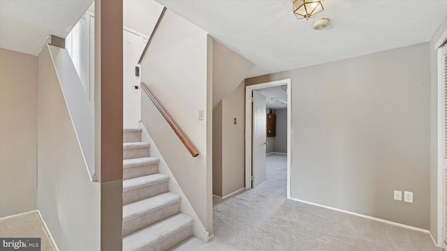 stairway featuring carpet flooring, a textured ceiling, and baseboards