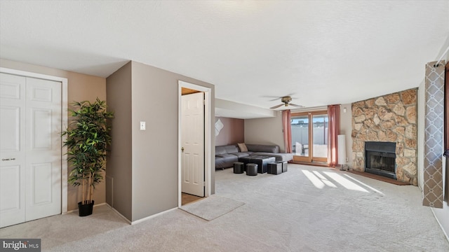 living area with ceiling fan, a fireplace, a textured ceiling, and carpet