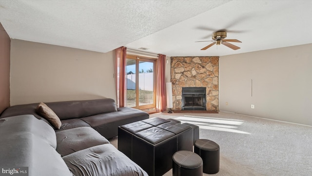 carpeted living area featuring visible vents, a ceiling fan, a textured ceiling, a stone fireplace, and baseboards