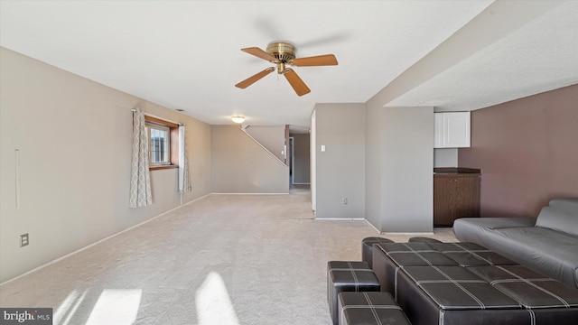 living room with baseboards, light colored carpet, and ceiling fan