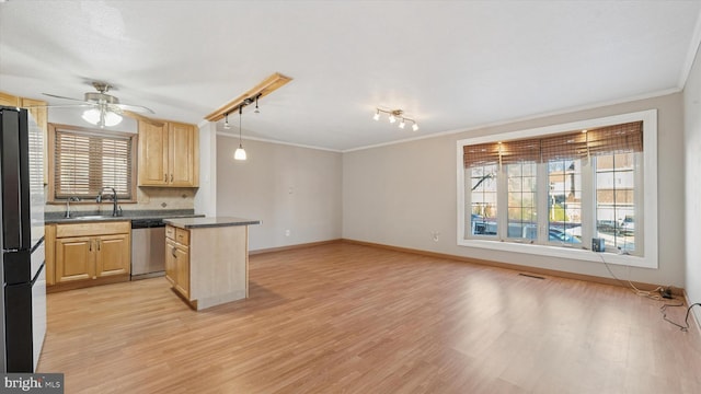 kitchen featuring stainless steel dishwasher, a sink, freestanding refrigerator, and light brown cabinetry