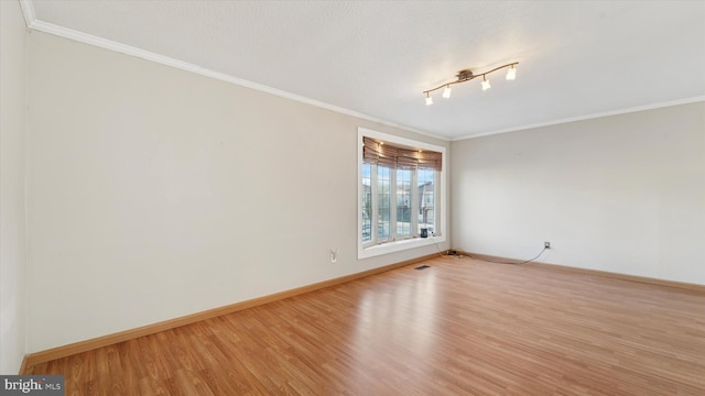 empty room with visible vents, baseboards, light wood-style floors, and crown molding