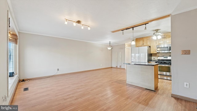 kitchen featuring dark countertops, tasteful backsplash, light brown cabinets, light wood-type flooring, and appliances with stainless steel finishes