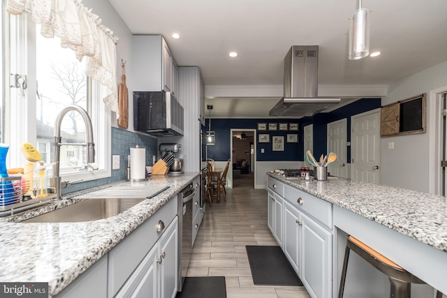 kitchen with sink, island range hood, decorative light fixtures, and white cabinets