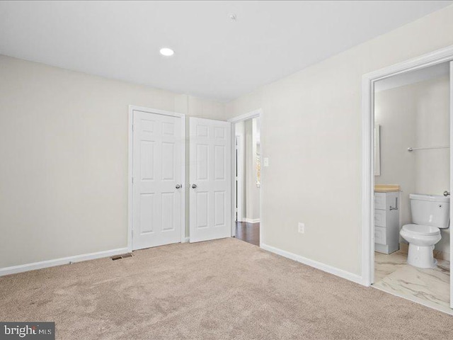 unfurnished bedroom with connected bathroom, light carpet, and a closet