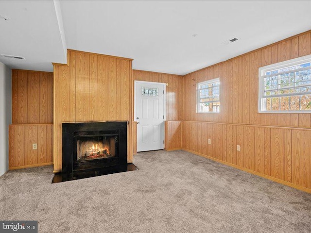 unfurnished living room featuring wooden walls, light colored carpet, and a fireplace