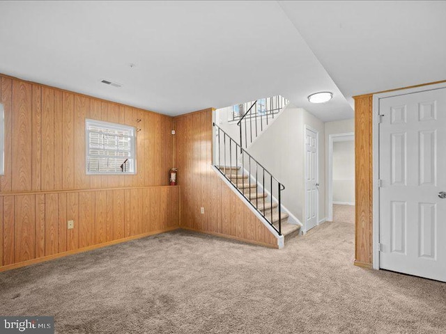 unfurnished room featuring carpet flooring and wooden walls