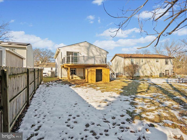 snow covered back of property featuring a deck