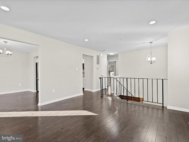 empty room with dark hardwood / wood-style floors and a chandelier