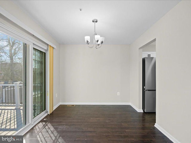 unfurnished dining area with dark wood-type flooring and an inviting chandelier