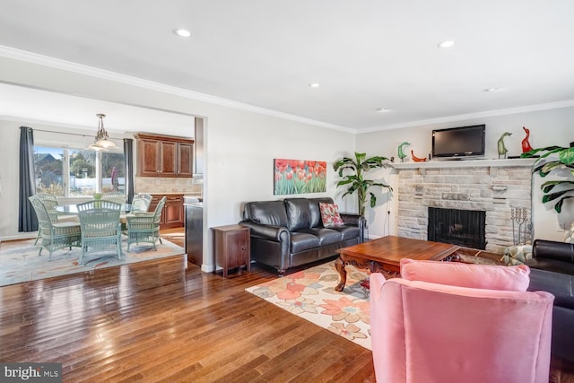 living room with crown molding, a stone fireplace, and dark hardwood / wood-style floors