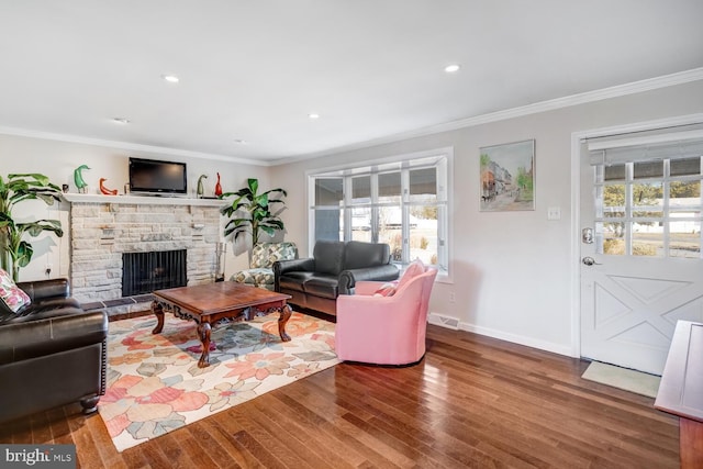 living room with hardwood / wood-style floors, crown molding, a wealth of natural light, and a fireplace