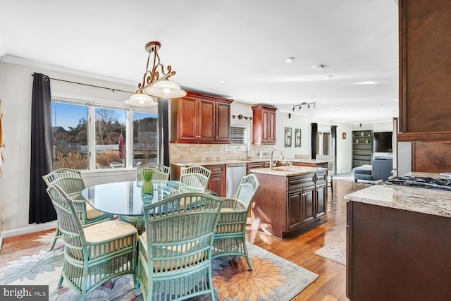 dining area with ornamental molding, sink, and light hardwood / wood-style floors