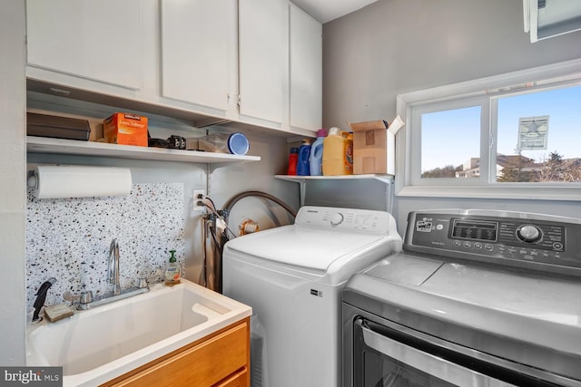 laundry area with cabinets, independent washer and dryer, and sink