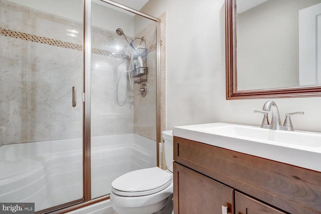 bathroom featuring vanity, a shower with shower door, and toilet