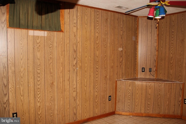 interior space with ceiling fan, wooden walls, and a textured ceiling