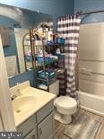 full bathroom featuring toilet, vanity, and shower / bathtub combination with curtain