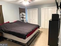 bedroom with multiple closets, ceiling fan, and light carpet