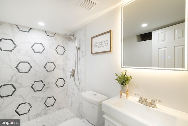 bathroom with vanity, toilet, and a tile shower