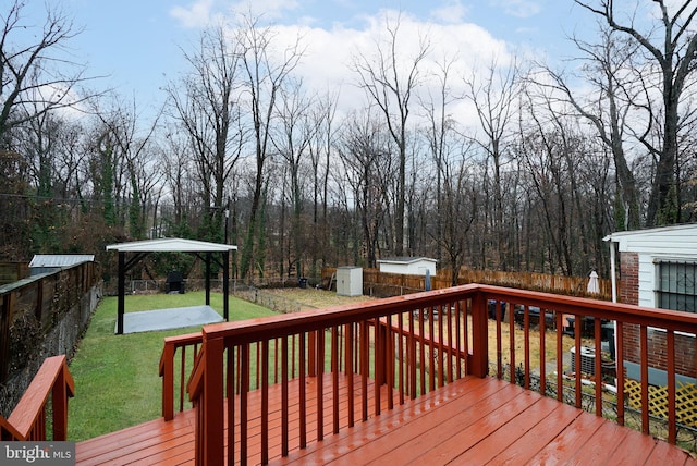 wooden terrace with a gazebo, a yard, and a storage unit