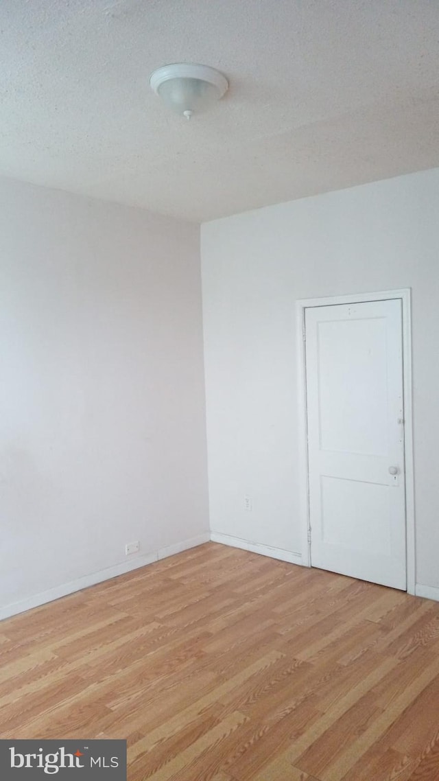 empty room with light hardwood / wood-style floors and a textured ceiling