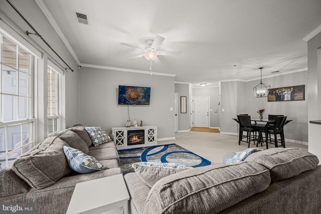 living room with ceiling fan with notable chandelier, a fireplace, ornamental molding, and light wood-type flooring