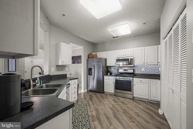 kitchen featuring stainless steel appliances, tasteful backsplash, sink, and white cabinets