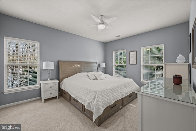 bedroom featuring a textured ceiling, light colored carpet, and ceiling fan