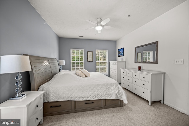 bedroom with a textured ceiling, light colored carpet, and ceiling fan