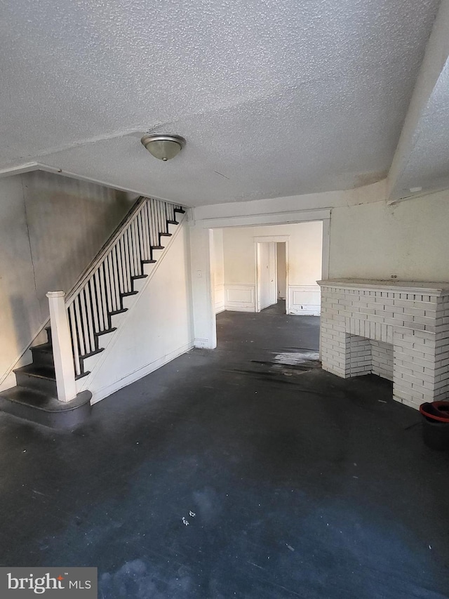 unfurnished living room featuring a brick fireplace and a textured ceiling