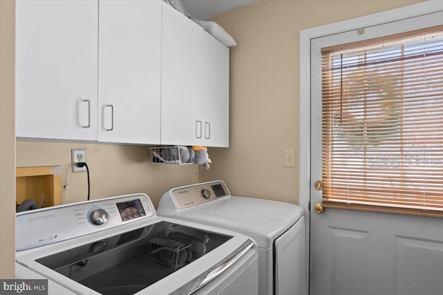 clothes washing area featuring cabinets and washer and dryer