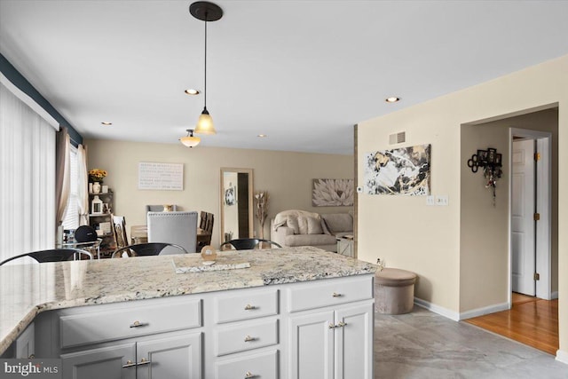 kitchen with pendant lighting, light stone counters, and white cabinets