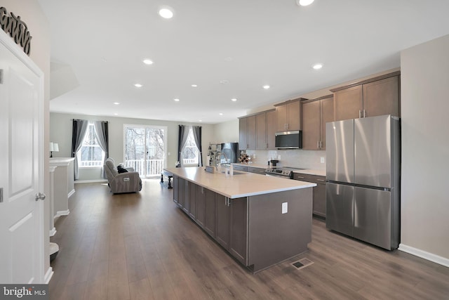 kitchen featuring dark hardwood / wood-style floors, sink, backsplash, a kitchen island with sink, and stainless steel appliances