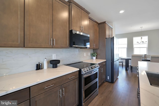 kitchen with light stone countertops, appliances with stainless steel finishes, dark hardwood / wood-style floors, and decorative light fixtures