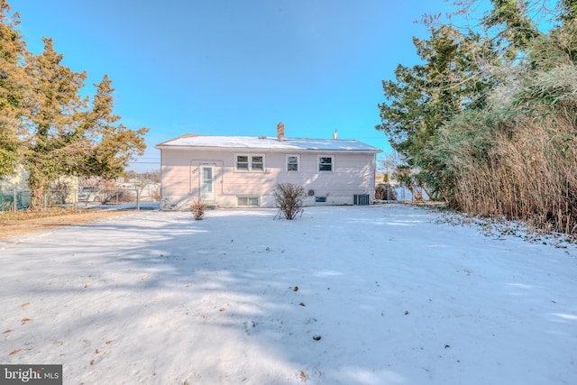 snow covered rear of property featuring central AC unit