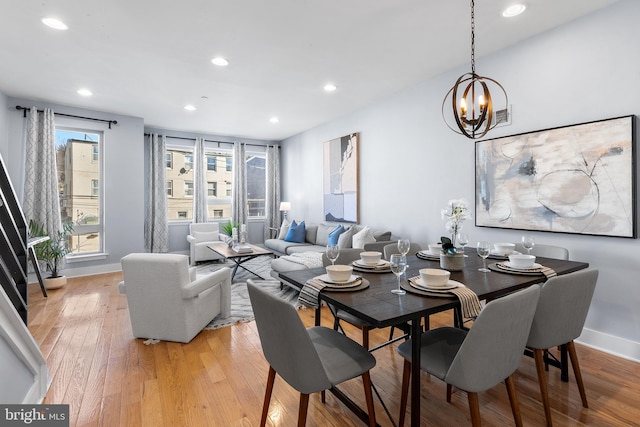 dining space with a notable chandelier and light hardwood / wood-style flooring