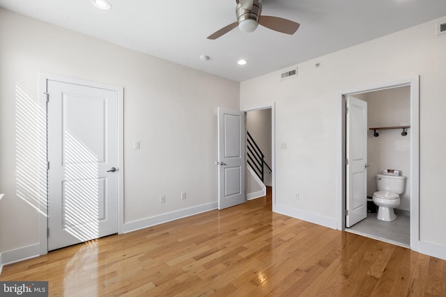 unfurnished bedroom with ensuite bathroom and light wood-type flooring