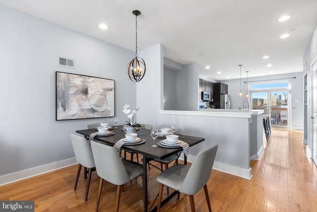 dining area featuring an inviting chandelier, sink, and light wood-type flooring