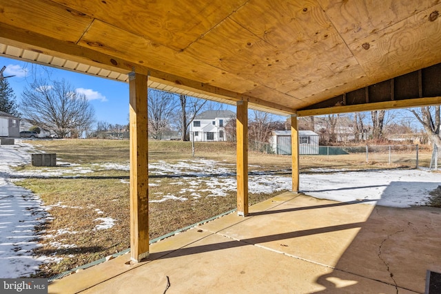 snow covered patio with a storage shed