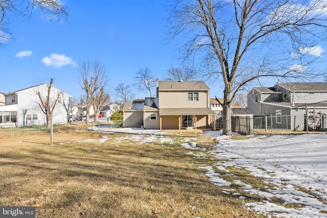 snow covered back of property featuring a yard