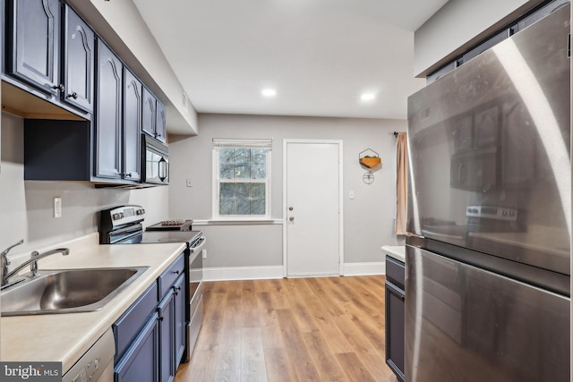 kitchen featuring stainless steel appliances, blue cabinetry, sink, and light wood-type flooring