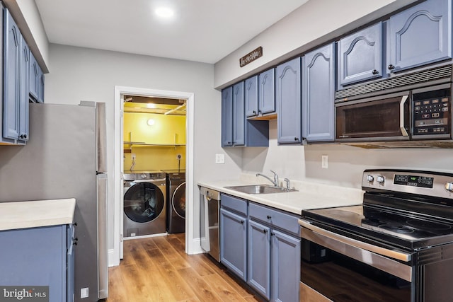 kitchen featuring appliances with stainless steel finishes, blue cabinetry, sink, and washing machine and clothes dryer