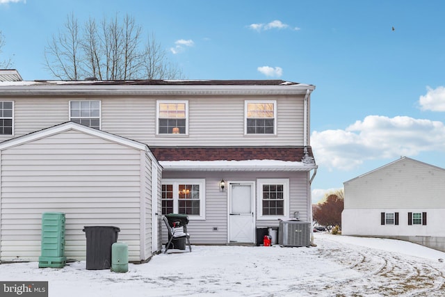 snow covered rear of property featuring central air condition unit