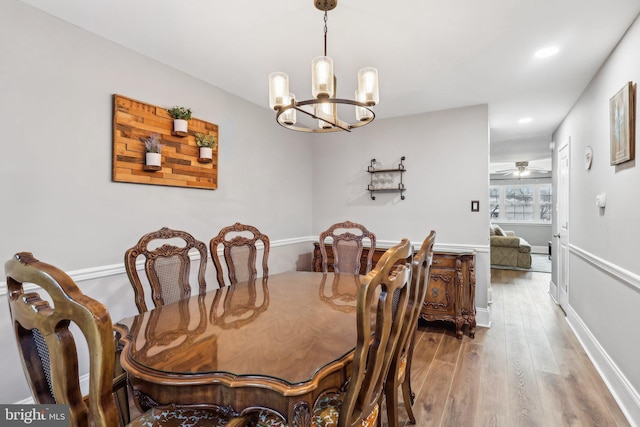 dining room featuring hardwood / wood-style flooring and ceiling fan with notable chandelier