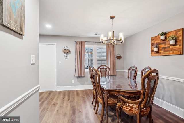 dining room with hardwood / wood-style flooring and a notable chandelier