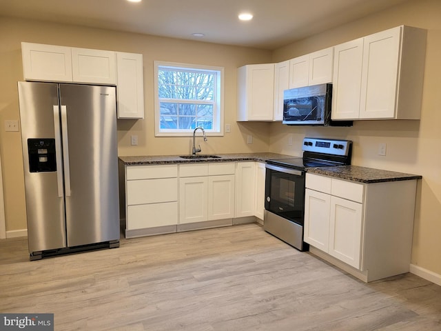 kitchen featuring stainless steel appliances, sink, light hardwood / wood-style flooring, and white cabinets